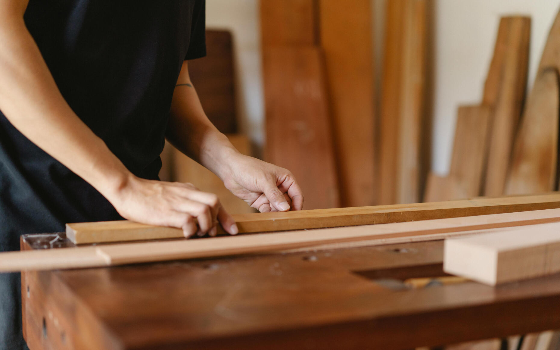 Atelier ébénisterie Main de femmes tenant une planche en bois dans un décor d'atelier d'ébénisterie